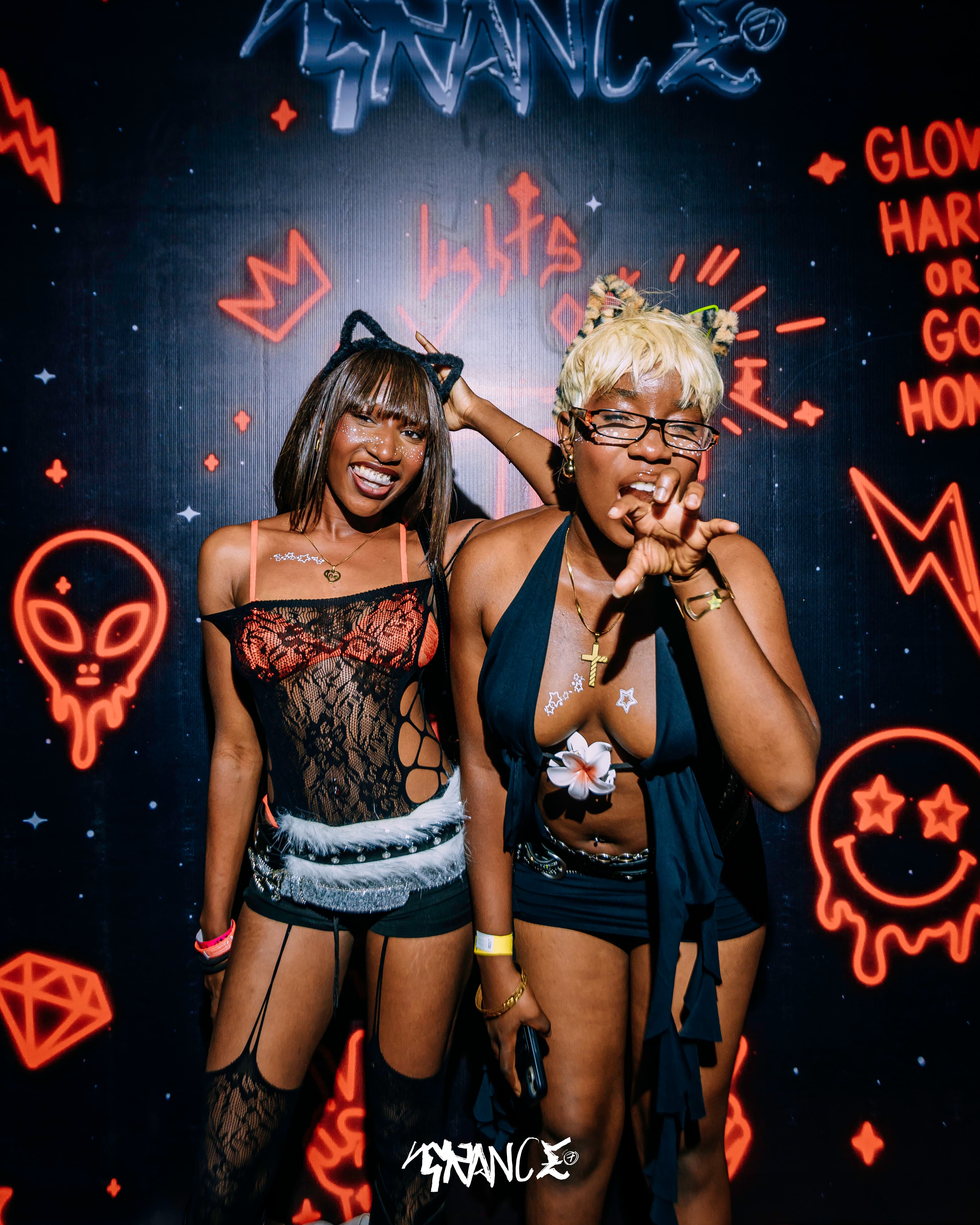 Two guests posing in front of a red illustrated Trance backdrop